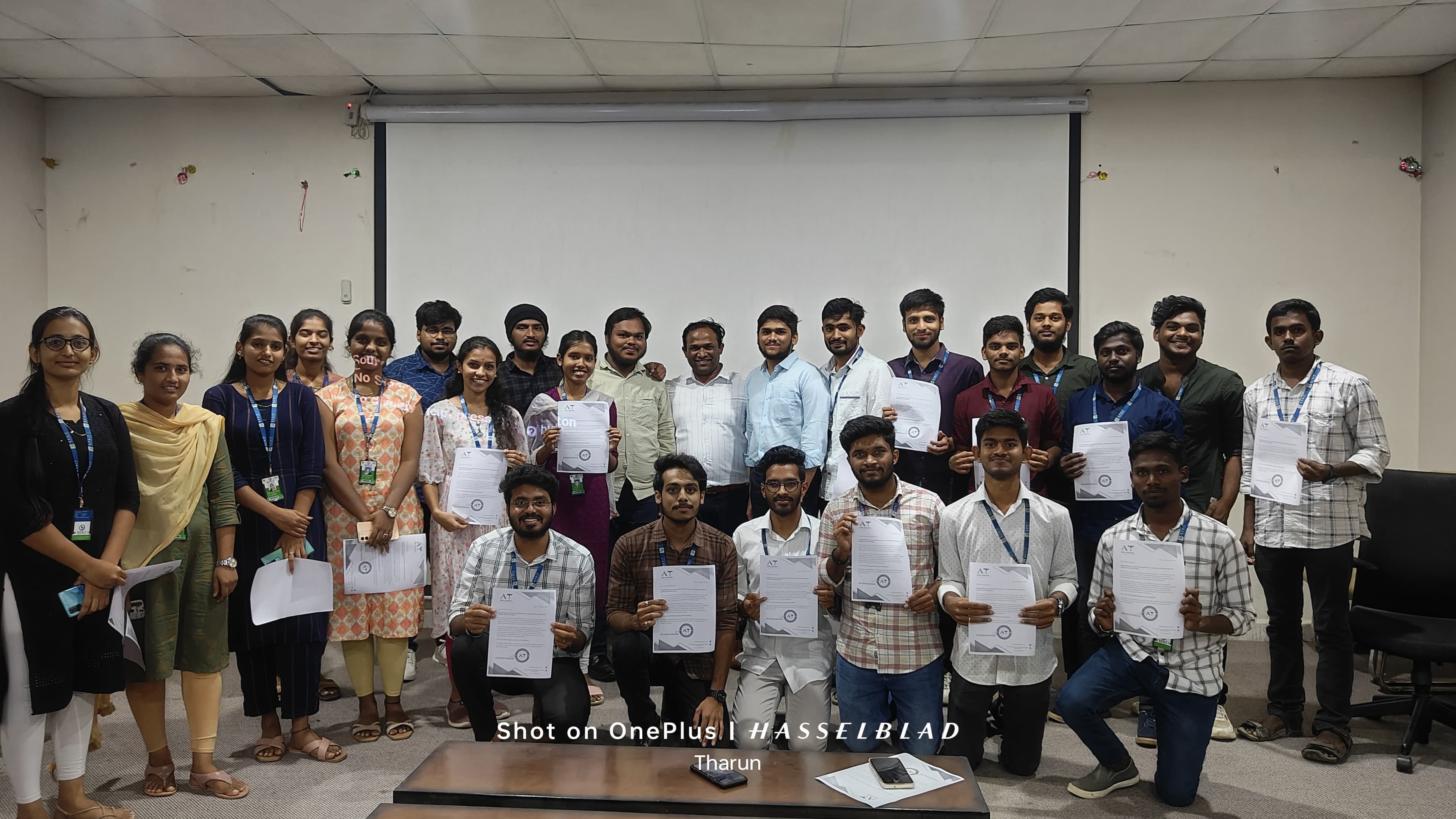 A cohort of Sraventix trainees holding their course completion certificates in a training hall