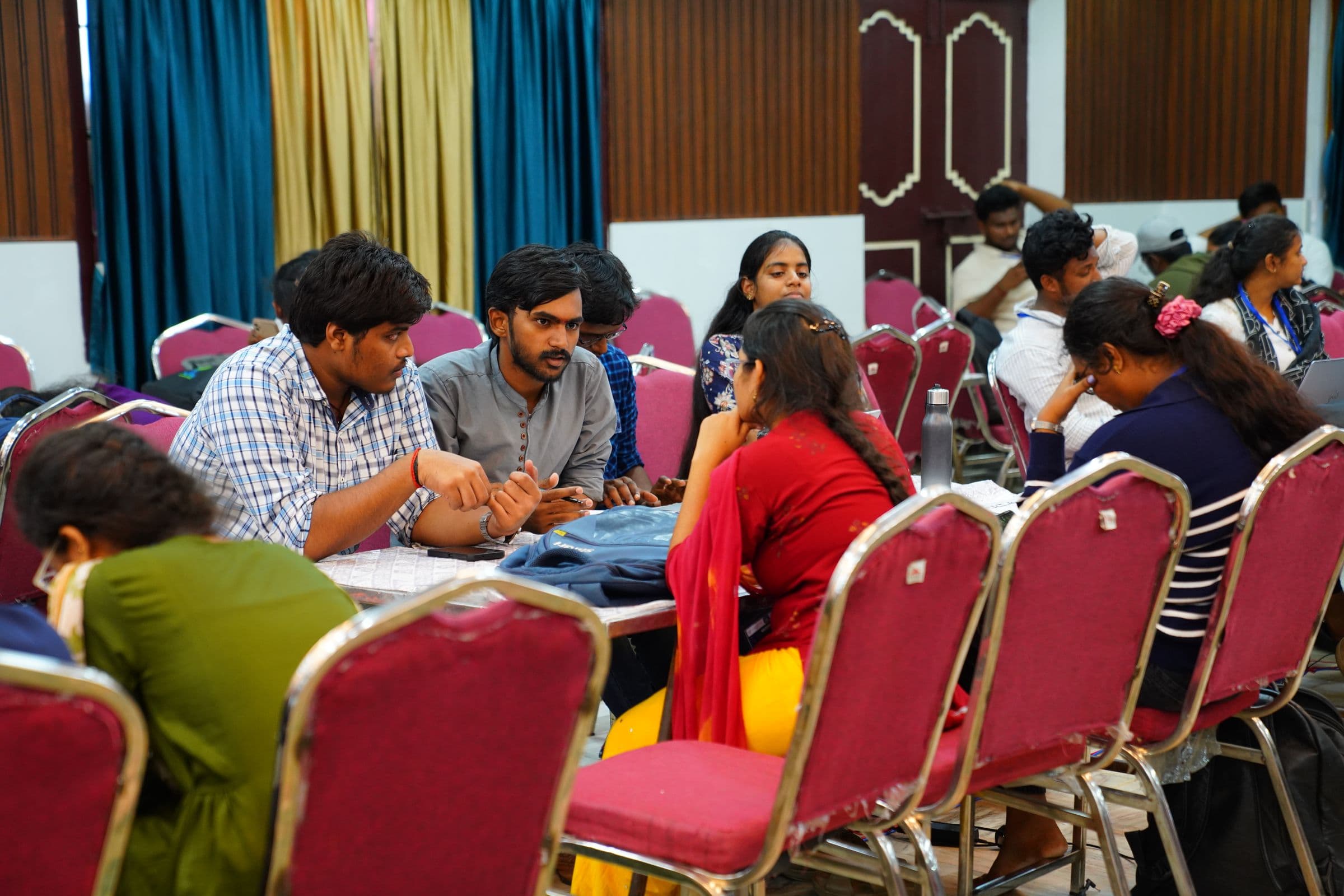 Participants huddled around a table, mentoring and refining their project